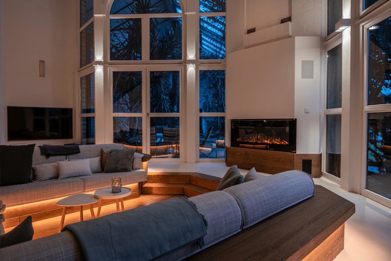 Modernes Wohnzimmer mit grauen Sofas, Kamin und großen Fenstern