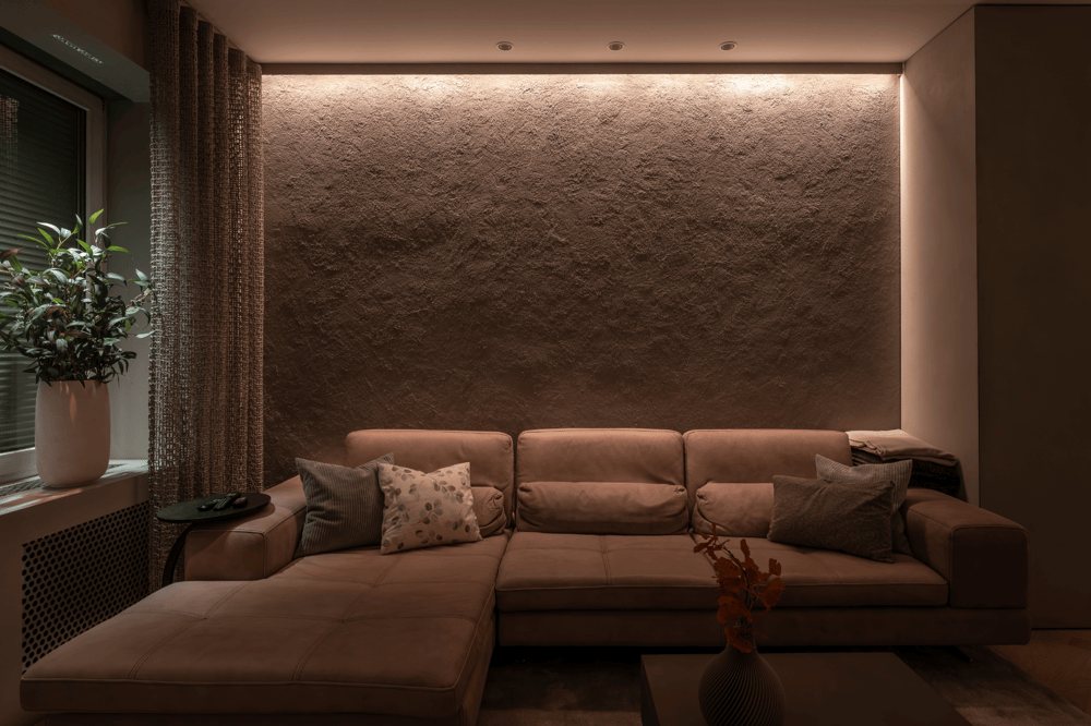 Braunes Ecksofa vor strukturierter, beleuchteter Wand