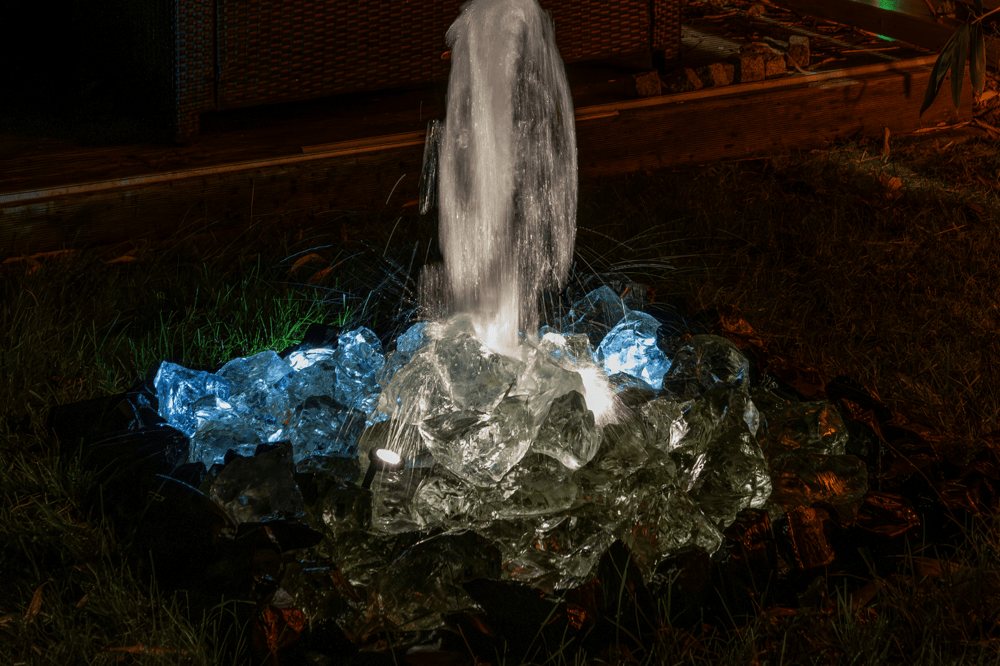 Wasserspiel mit sprudelndem Wasser und Lichtakzenten