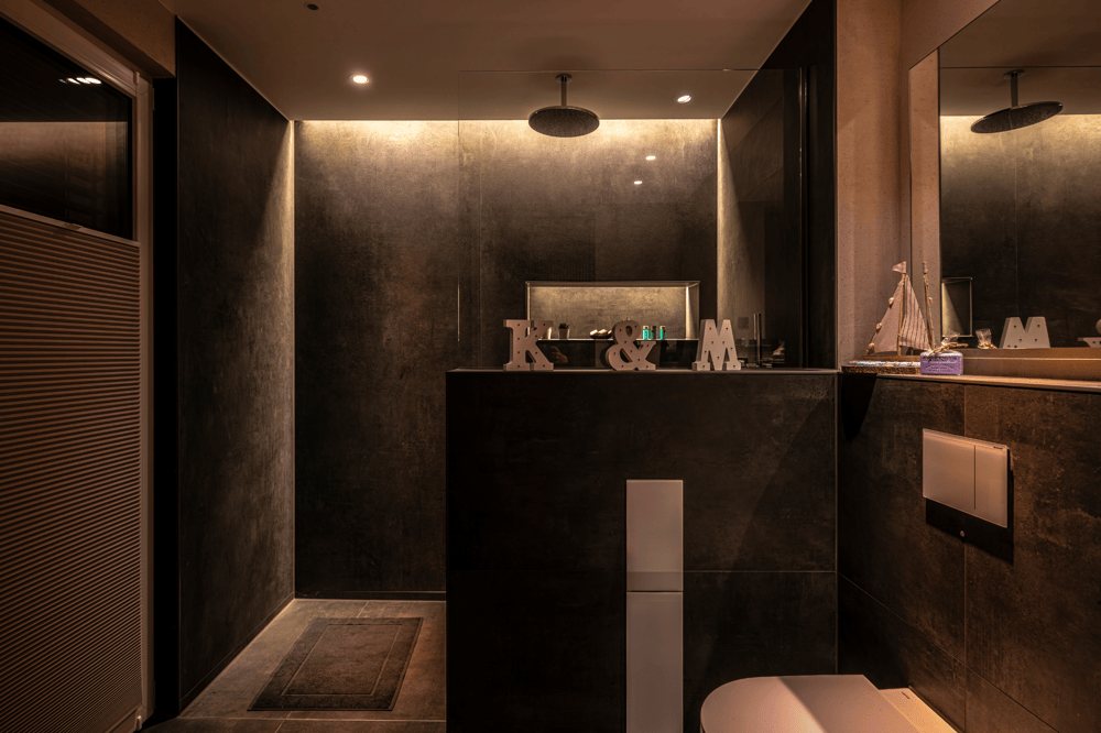 Dunkles Badezimmer mit grauen Fliesen und begehbarer Dusche